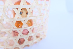 a Russian dolls showing a sad woman imprisoned in a light wooden cage on white background