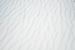 Wavy texture of white sands blown in the wind.