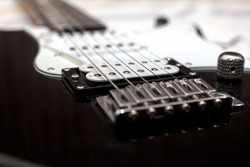 Black electric guitar bridge and stings in closeup