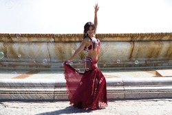 A young and beautiful belly dancer dancing in a square. She is dressed in light blue with a white veil in her hands. World folklore concept from Africa and Asia.