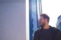 young and handsome man with beard, sculptural body and sunglasses is leaving the office where he works in a glass building. Concept management, administration, office, company, boss.
