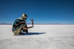 Couple playing in the desert salt flats, having fun with perspective