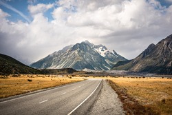 Mount Cook or Aoraki National park with road over the mountain and the cloudy sky in background