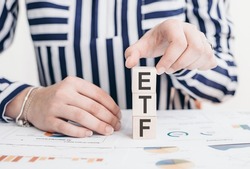 Exchange Traded Fund or ETF concept. Holding the top of wooden cube standing with ETF text.