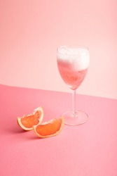 glass with sparkling rosé wine and grapefruit on pink background- Pink cocktail 