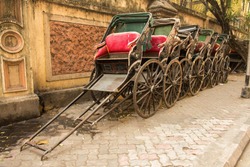 Traditional hand pulled Indian rickshaws parked together in front of a old building in Kolkata
