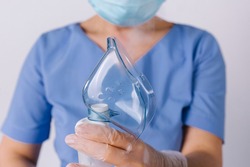 Cropped photo. Doctor's hands holding a respiratory mask on a white background. Respiratory and allergy treatment.