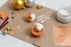 Creative DIY workshop with Christmas homemade white balls decorated with gold leaf. Christmas craft, recycle idea. Tools for creating holiday decoration - modern glam trend. Top view.