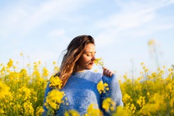 Young woman smelling yellow flowers in a field