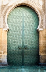Famous landmark in Spain. Beautiful cathedral Mezquita of Cordoba, Andalucia. Green door with arch in old arabic style. Traditional spanish architecture. Religious and tourist place in Europe.