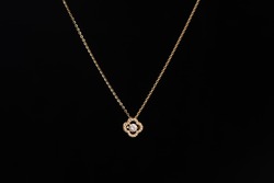 Golden chain necklace with diamond pendant on black background