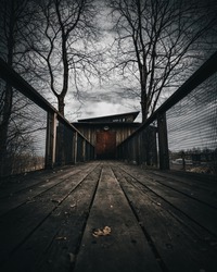 Low angle view of wooden bridge leading to mystery door. Dramatic cine like edit.