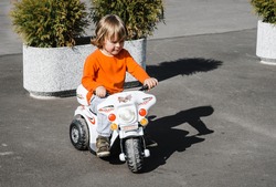 boy rides on a children's toy motorcycle on an asphalt road. child on a walk in the fresh air outdoor activities.
