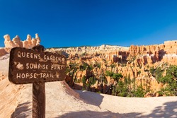Sign giving directions for the most famous attractions of Bryce Canyon National park amphitheater area. In the background hoodoos and red rocks are visible during a sunny summer day