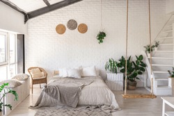 
Luxury bedroom design in a rustic cottage in a minimalist style. white walls, panoramic windows, wooden elements of decoration on the ceiling, rope swings in the middle of a spacious room.
