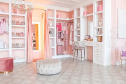 luxury interior of large room in pink colors with expensive furniture in rich barocco style decorated with flowers in vases. wardrobe-room for clothes, shoes and various personal items