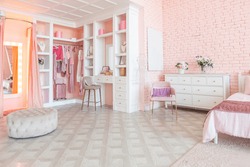 luxury interior of large room in pink colors with expensive furniture in rich barocco style decorated with flowers in vases. wardrobe-room for clothes, shoes and various personal items