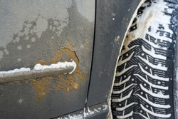 Rust on a car close-up from de-icing reagents. The concept of harm from reagents for the environment