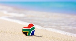 Flag of South Africa in the shape of a heart on a sandy beach. The concept of the best vacation in South Africa.