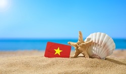 Tropical beach with seashells and Vietnam flag. The concept of a paradise vacation on the beaches of Vietnam.