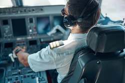 Top view of man in aviation uniform and earphones sitting at control and switching rudder while taking off