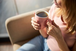 Young woman holding pink cup of coffee