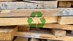 Green recycling icon on waste wood planks from construction site, sort and reuse abandoned materials, sustainable responsible development concept, creative environmental protection symbol background