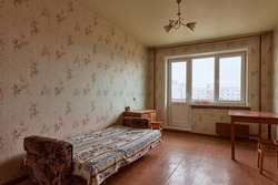 Example of Old Soviet Russian poor interior in Leningrad project House. Aged  sideboard, table, chairs, bed. Shabby floor. Tattered wallpaper on the wall. Apartment of pensioners. Selective focus.