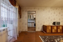 Example of Old Soviet Russian poor interior in Khruschev House. Aged sideboard, tv set, curtains, kitchen furniture. Shabby floor. Tattered wallpaper on wall. Carpet as decor. Apartment of pensioners.