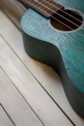 Close up of acoustic ukulele; ukulele strings, saddle, soundhole, ukulele body, neck, fretboard. Fretted folk instrument, wooden, inlay.