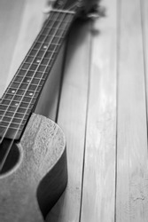 Close up of acoustic ukulele; ukulele strings, saddle, soundhole, ukulele body, neck, fretboard. Fretted folk instrument, wooden, inlay.

