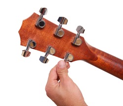 Person tuning a guitar from its  headstock over white background
