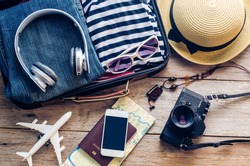 Clothing traveler's Passport, wallet, glasses, smart phone devices, on a wooden floor in the luggage ready to travel.