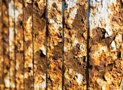 Metal bridge railing with corrosion, rust, deep cracks, and paint flaking texture