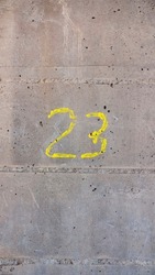 Number 23 written in yellow paint in concrete wall