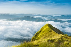 
Wide shot of beautiful landscape of magical green hills on top of a mountain. view of clouds from above a hill with the sea in the background. Trip in Eramon El salvador