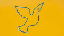 Photograph of the silhouette of the drawing of a flying bird in blue color on a yellow background