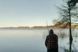 Latino senior from back fishing in a large lake