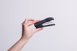 Stapler in the hands of a girl on a white background, stationery. High quality photo