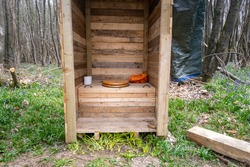 Close up of a rustic outdoor toilet in a woodland scene.