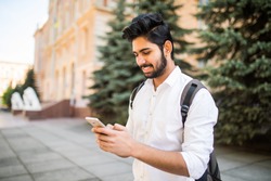 Indian male student texting on smartphone in the street