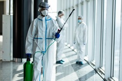 Disinfection, decontaminating due to coronavirus covid19 contagion. Hygiene specialist in protective clothing sprays disinfectant liquidin hospital