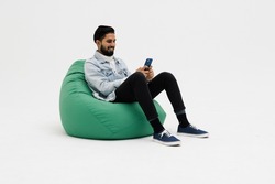 Young man sitting comfy soft violet armchair holding telephone chatting colleagues wear specs casual denim outfit isolated grey color background