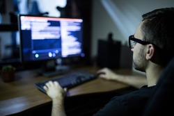 hacker in headset and eyeglasses with keyboard hacking computer system or programming
