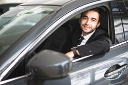 happy smiling driver in the car, portrait of young successful business man