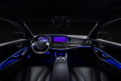 Car interior from driver seat view. Black leather cockpit with blue ambient light.