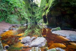 Finnich Glen.The Devil’s Pulpit in Scotland. UK. Steep glen from the red sandstone by the Carnock Burn. Circular rock known as the Devil's Pulpit and a steep staircase known as the Devil's Steps  