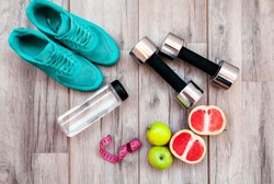 Fitness equipment. Healthy food. Sneakers, water,apple  on wooden background