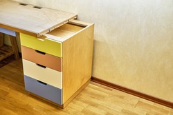 Plywood desk with multi color drawers during assembly. Fragment of the writing desk