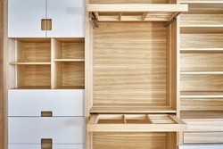 Internal details of the wooden wardrobe with slide out rack for coathangers. Oak veneered plywood cabinets with light gray painted cabinet doors. Detail of modern furniture